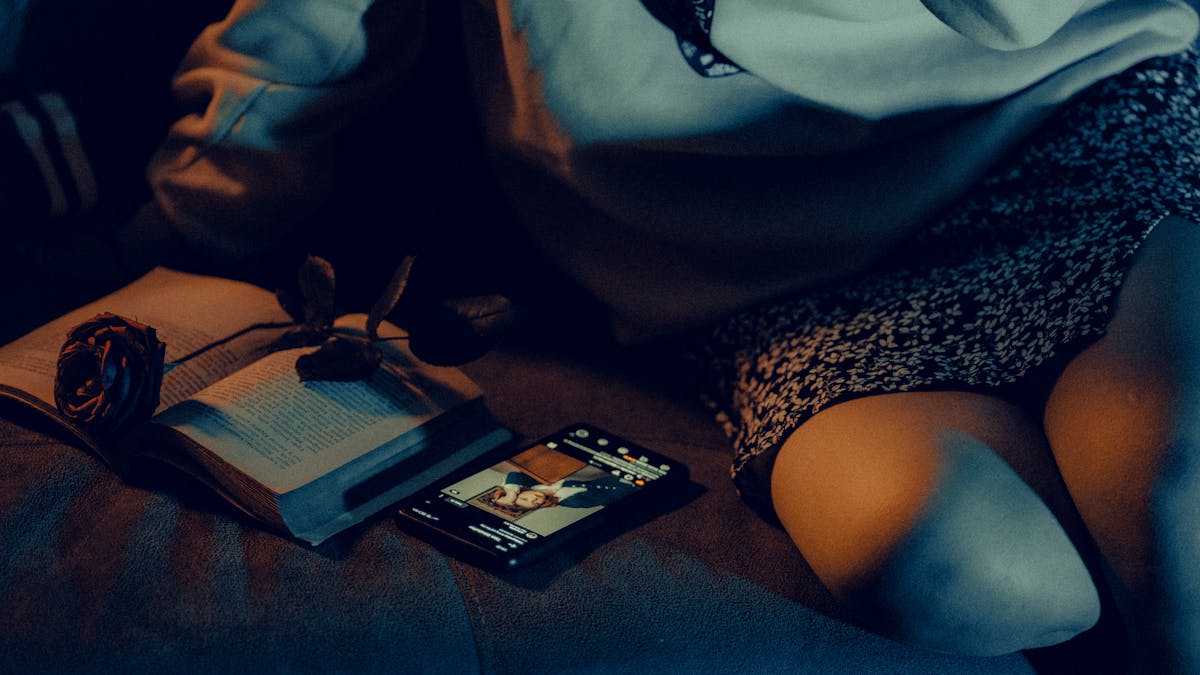Cozy scene with a book, smartphone, and low lighting conveying a relaxed evening at home.