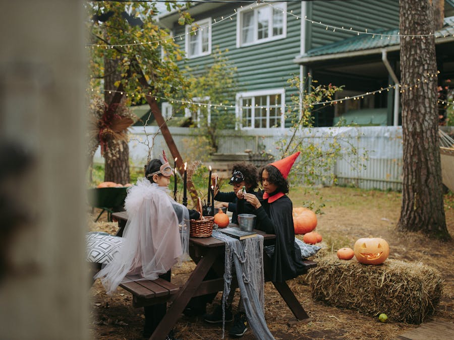 Children in Halloween costumes enjoying a festive outdoor party with pumpkins and decorations.