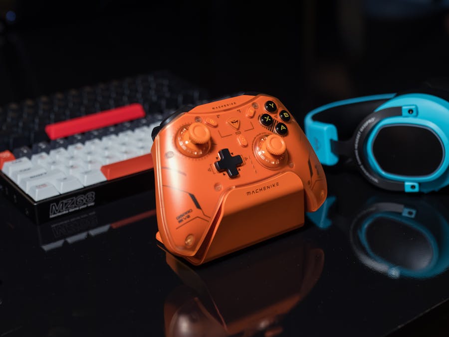 Dynamic gaming setup featuring an orange controller, keyboard, and blue headset.