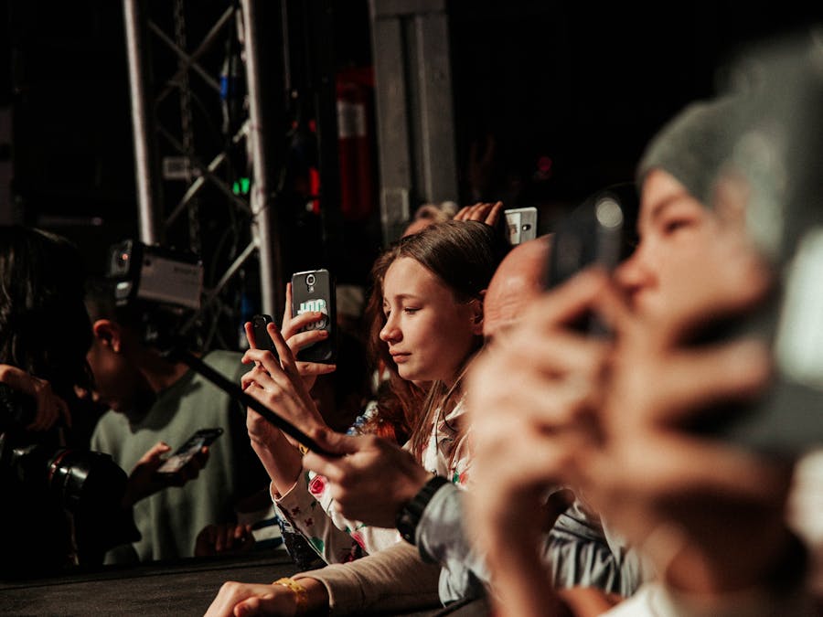 People eagerly capturing a live event on their smartphones, showcasing audience engagement.