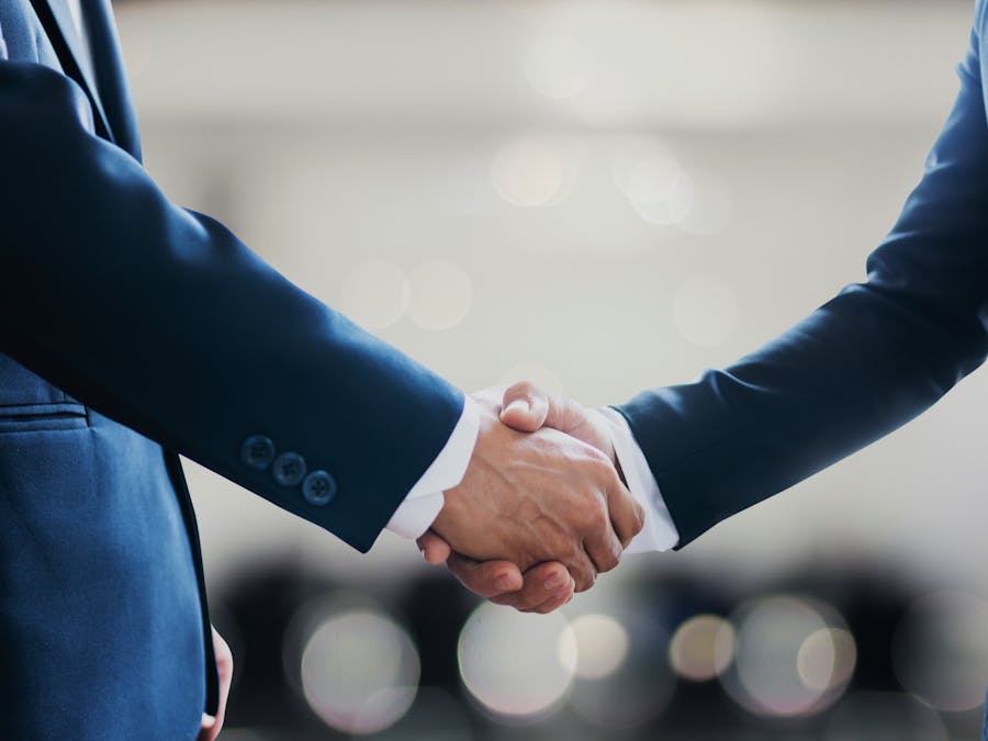 Close-up of business professionals in suits shaking hands, symbolizing a successful collaboration or agreement.