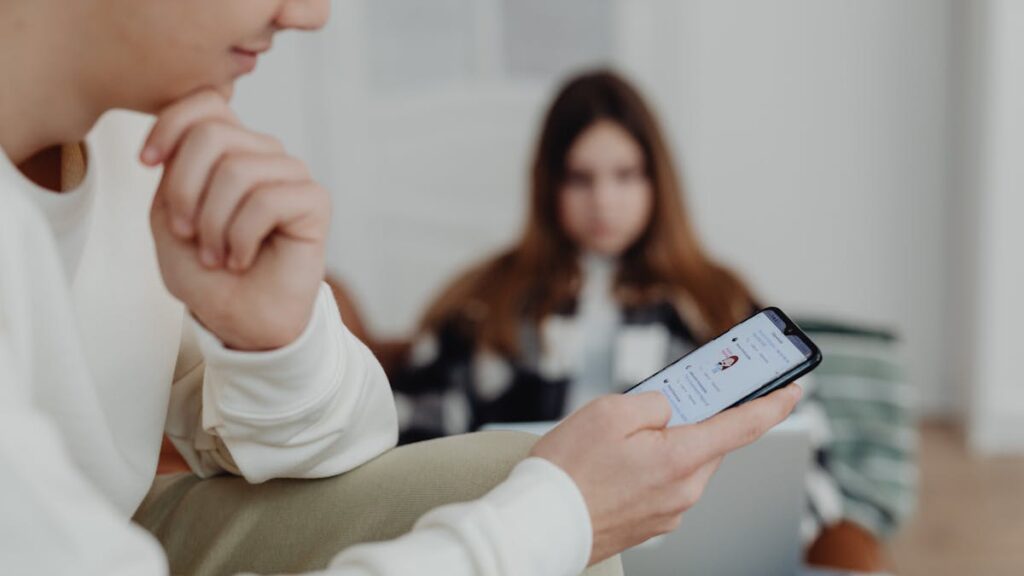 Teens using smartphones indoors with a blurred background, suggesting social media engagement.