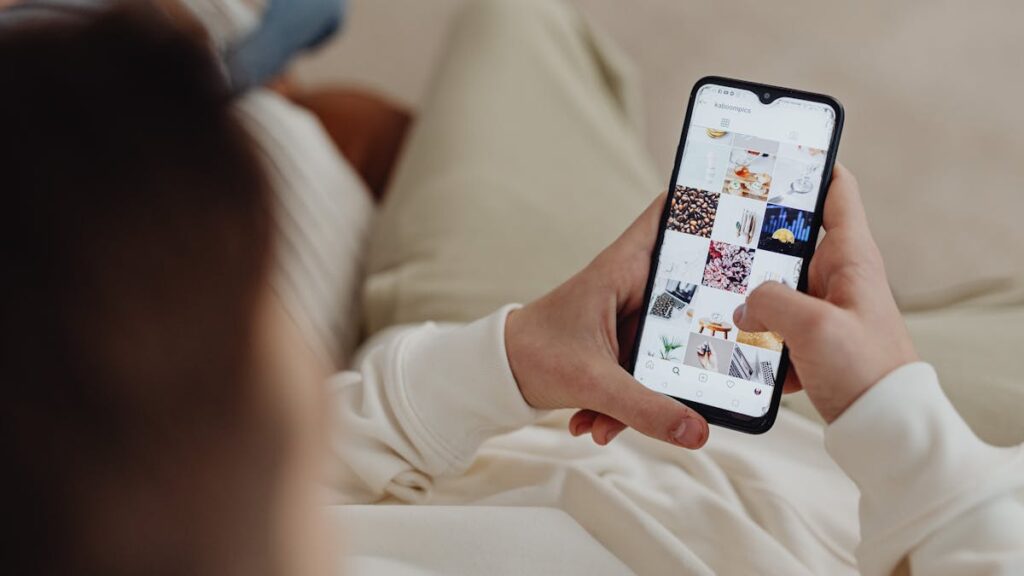 Person using smartphone to browse Instagram indoors, showing social media engagement.