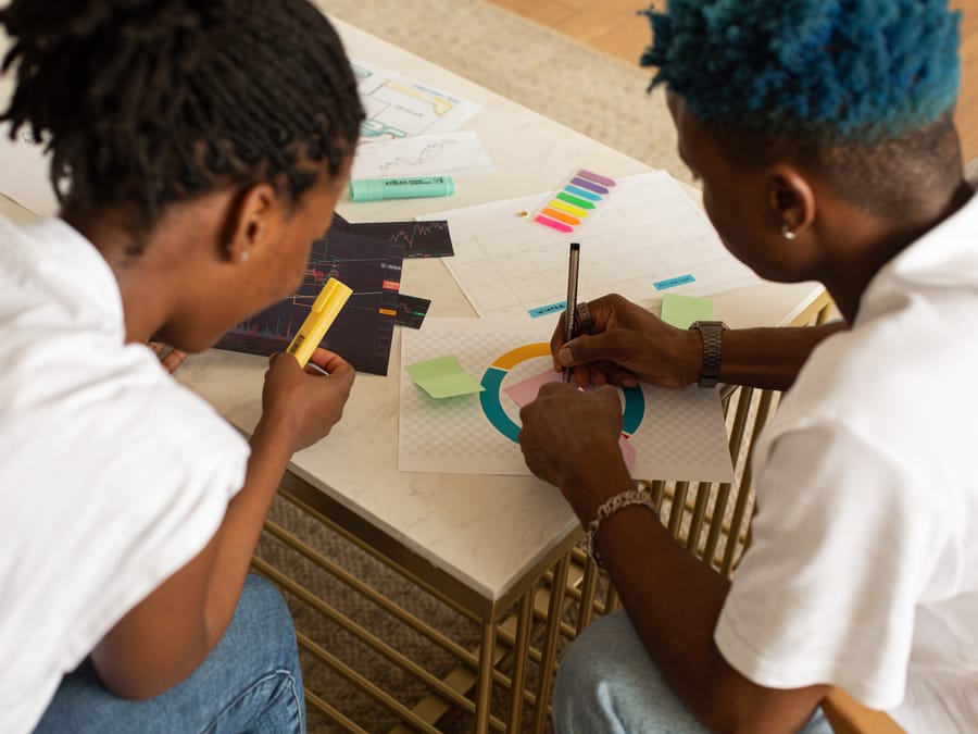 Two people collaborate on a creative project, analyzing charts and graphs.