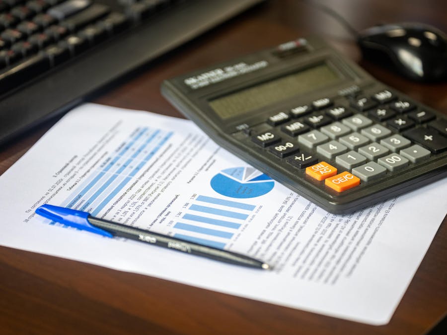 Desk with calculator, financial report, and pen, suggesting business analysis.