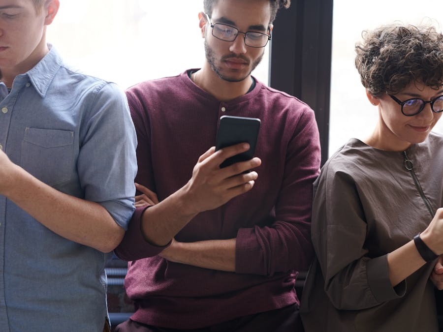 A diverse group of people actively using smartphones indoors. Modern technology and social interaction.