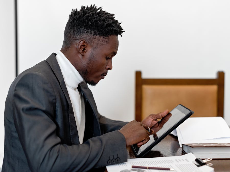 Businessman in elegant suit using tablet during office meeting, focusing on touchscreen technology.
