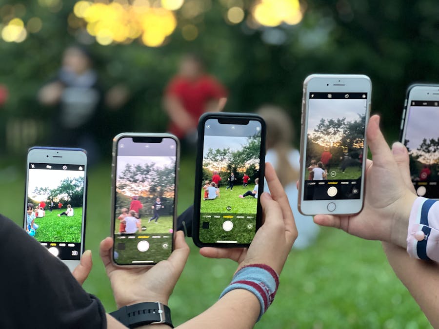 A group of people using smartphones to photograph an outdoor scene.