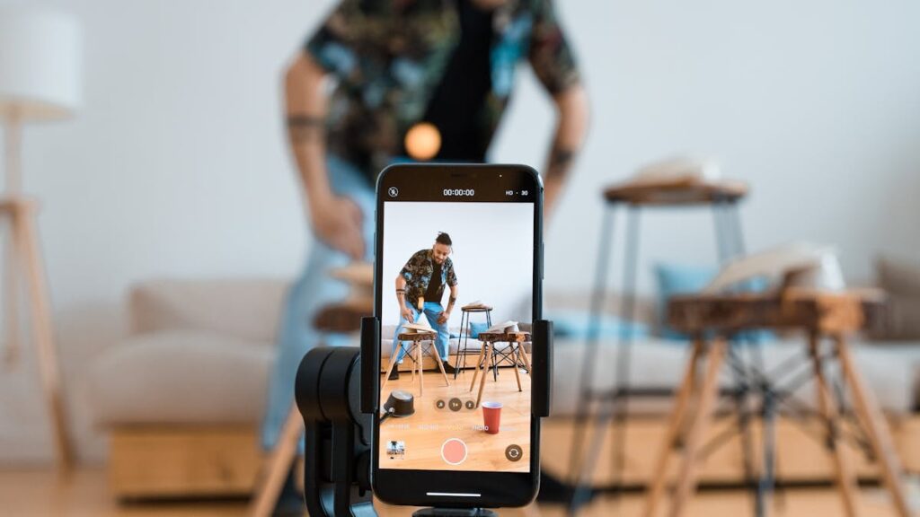 Man recording video content with smartphone on a tripod in a cozy living room.