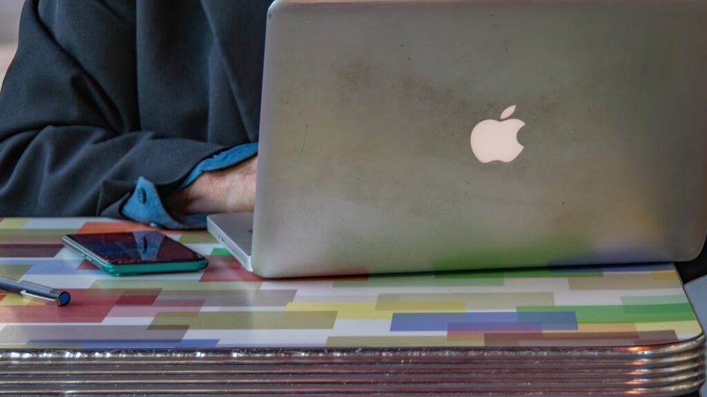 Close-up of a person using a laptop and smartphone on a colorful patterned table indoors.