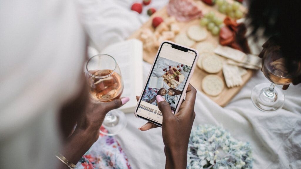 Overhead view of a picnic scene with people capturing moments using a smartphone.