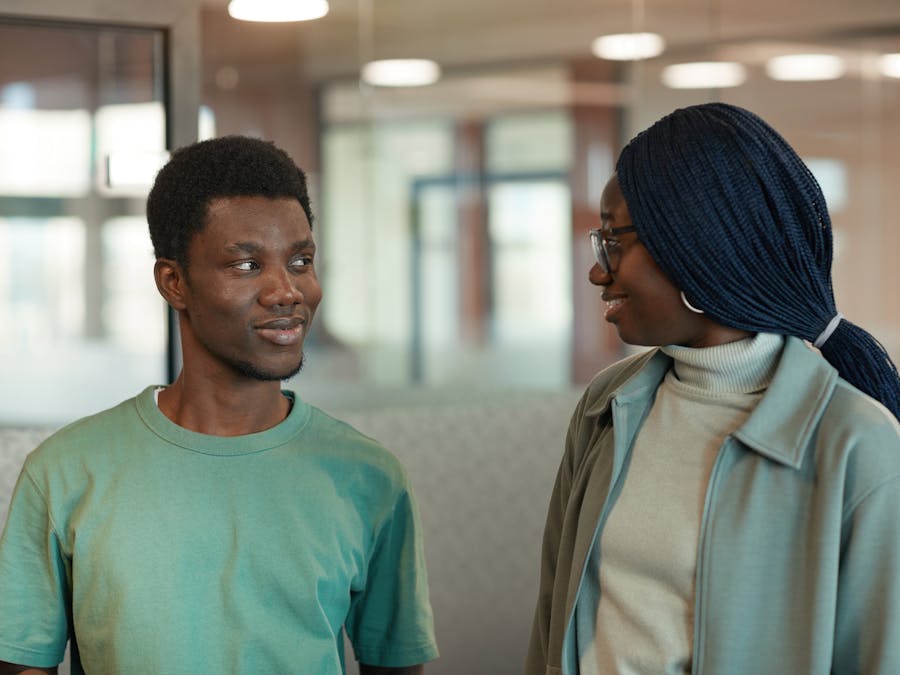 Two colleagues engaging in a friendly conversation indoors, expressing camaraderie and connection.