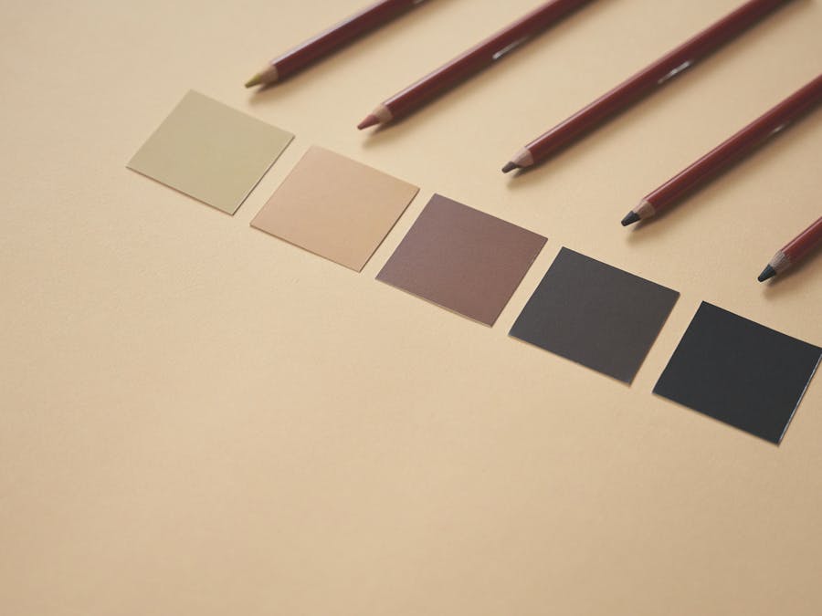 Creative arrangement of color swatches and pencils on a beige background, perfect for design concepts.