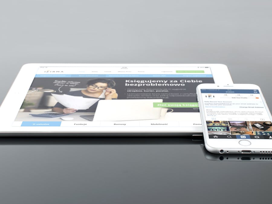 Modern tablet and smartphone displaying web content on a reflective surface, highlighting technology and connectivity.