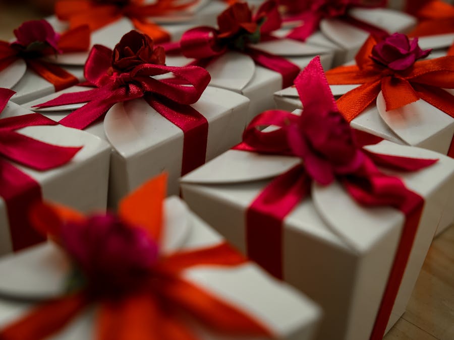 Close-up of white gift boxes adorned with vibrant red and orange ribbons, ideal for celebrations.