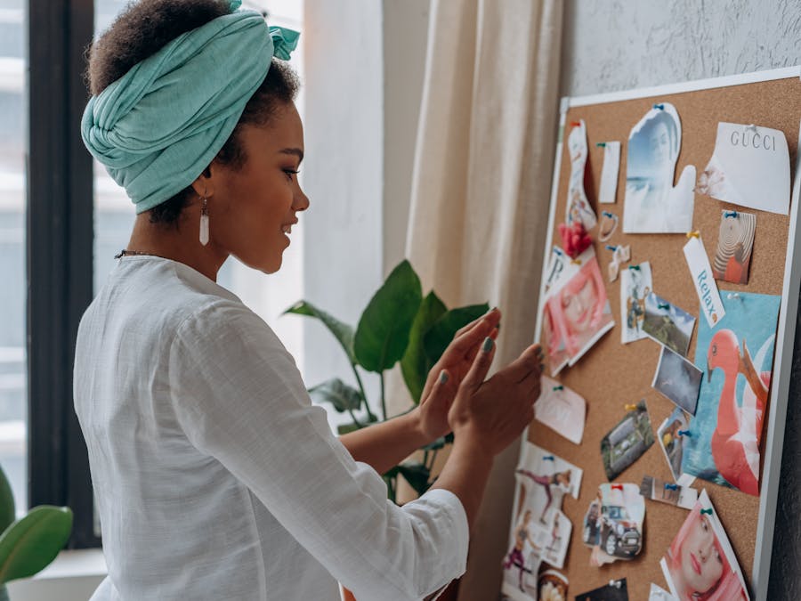 A woman arranging a creative mood board with diverse images and notes in a stylish interior.