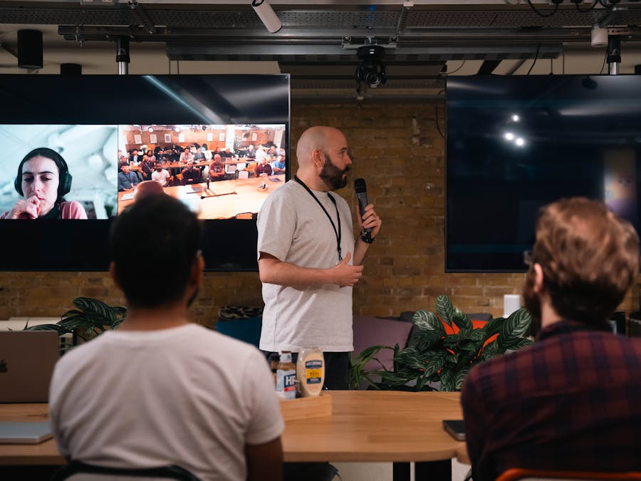 A business presentation featuring a speaker and interactive video call in an office setting.