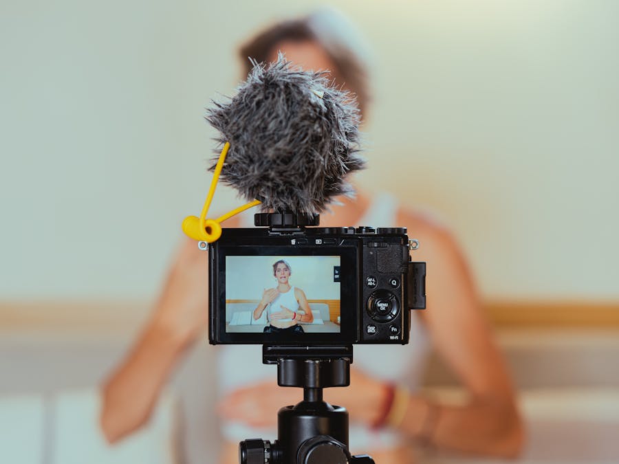 Elderly woman engages in vlogging using camera and microphone, embracing modern technology.