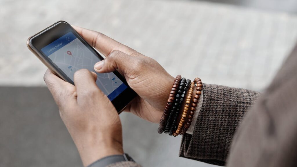 Close-up of hands with bracelets navigating on smartphone using GPS app outdoors.