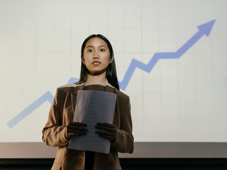 A confident businesswoman presenting a growth chart in a professional setting.