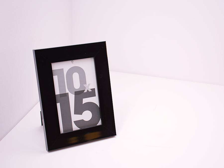 A stylish black photo frame standing on a white surface with minimalist design.