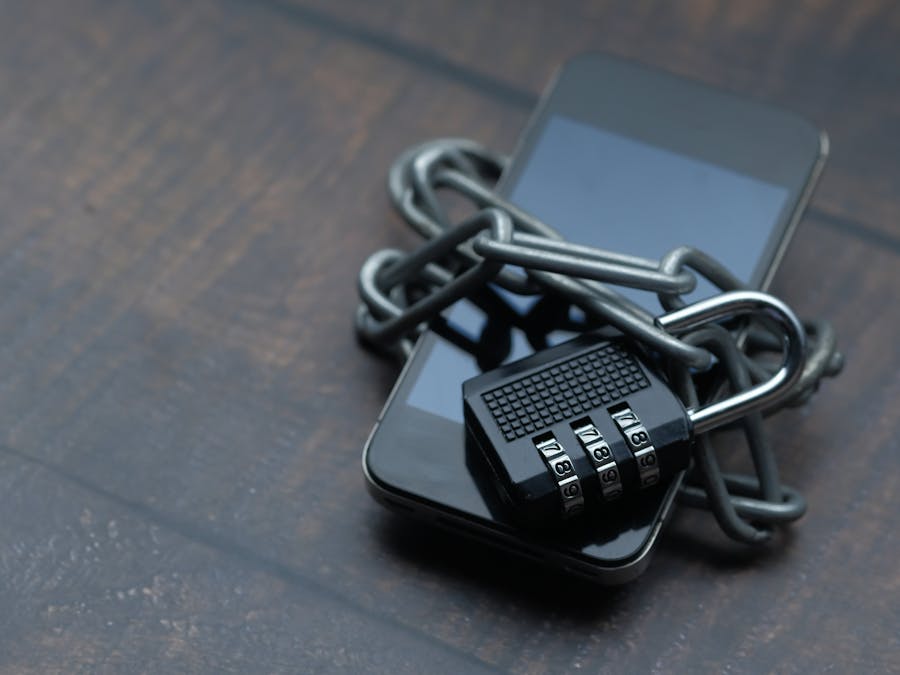 Close-up of a smartphone wrapped in a chain with a padlock, symbolizing strong security.