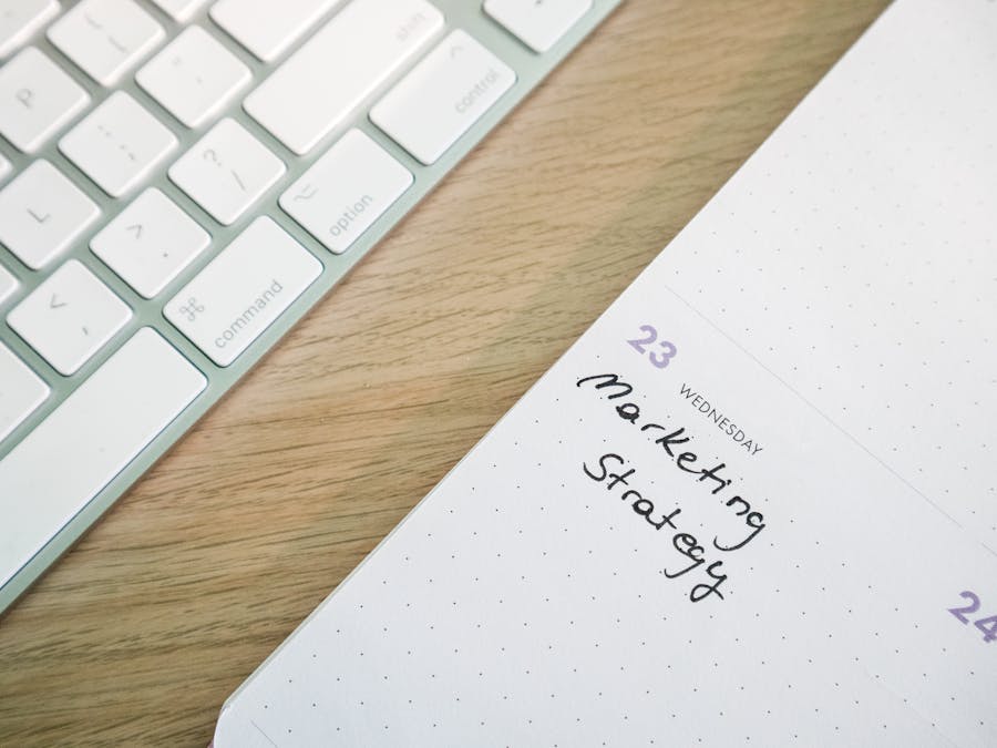 Close-up of a desk with a keyboard and a calendar open to a marketing strategy note.