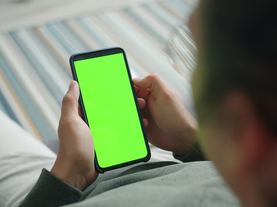 Close-up of person using phone with green screen for custom content display.