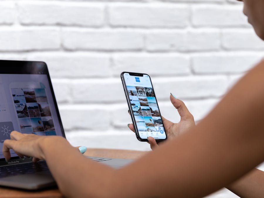 A woman working remotely using a laptop and smartphone, focusing on social media content.