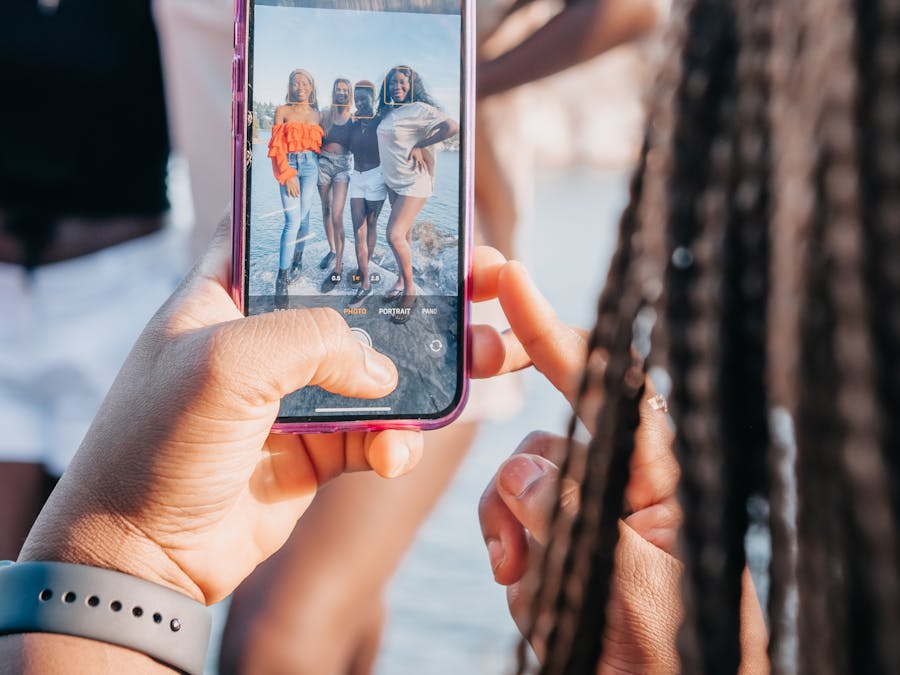 Group of friends taking a photo with a smartphone during a sunny day outdoors.