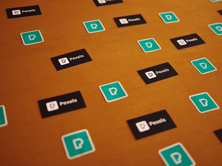 Pexels logos and stickers scattered on a brown background in a creative pattern.