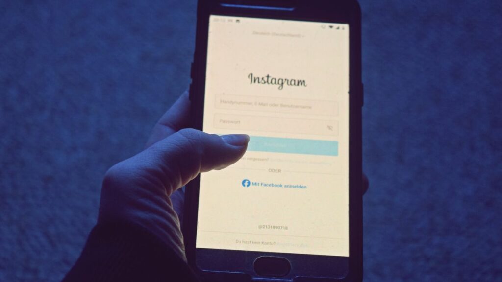 Close-up of a hand holding a smartphone displaying the Instagram login screen.