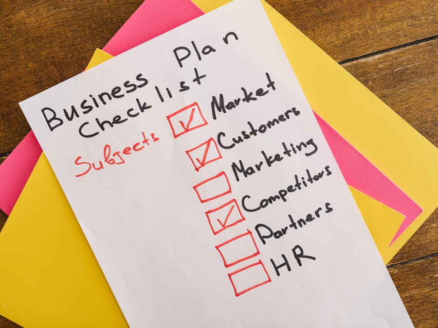 A handwritten business plan checklist on a table with colorful papers indicating important topics for startups.