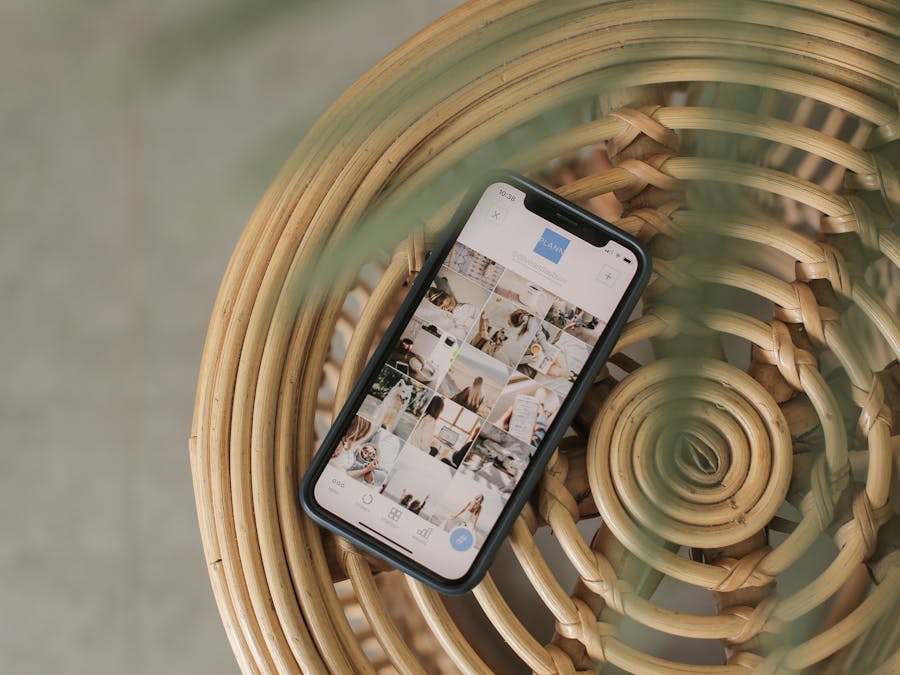 A smartphone displaying a social media app interface, placed on a wicker chair, creating a relaxed Bali vibe.