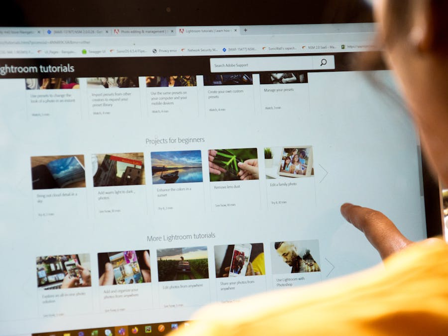 Woman exploring Lightroom tutorials on computer screen, perfect for online education themes.