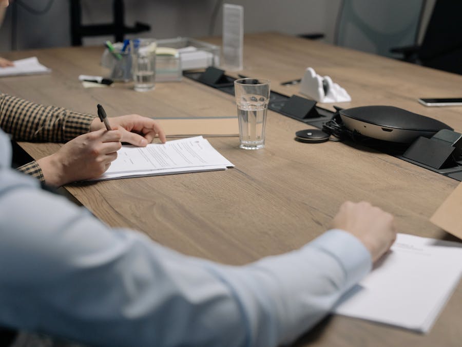 Professional setting of a business meeting with individuals signing documents on a conference table.