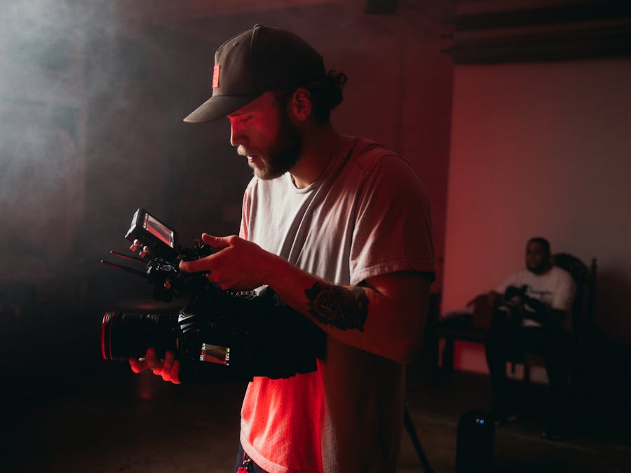 Professional cinematographer operating a camera indoors with dramatic lighting.