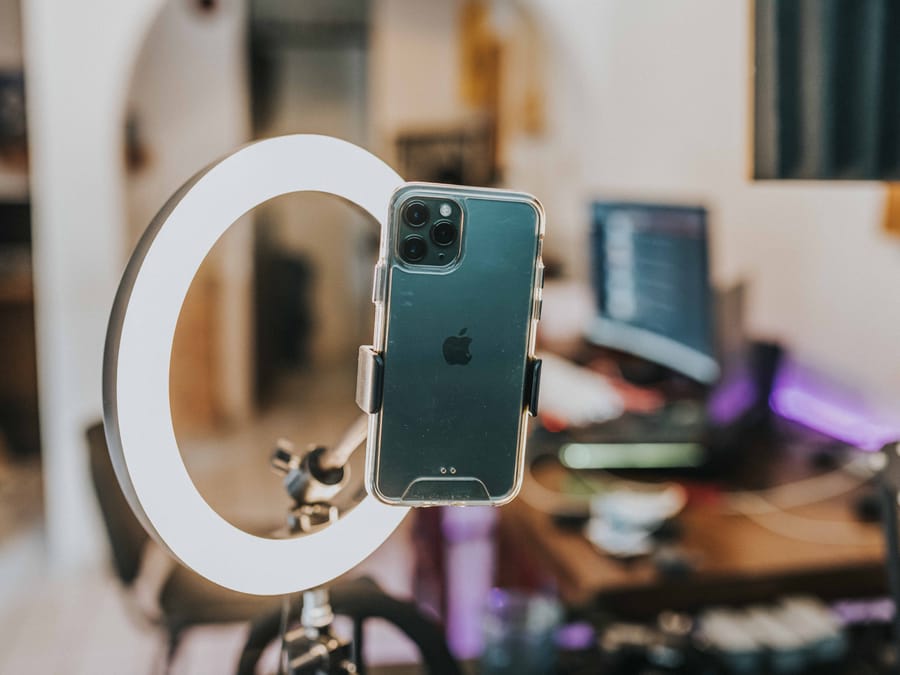 Smartphone mounted in ring light for content creation in modern workspace.