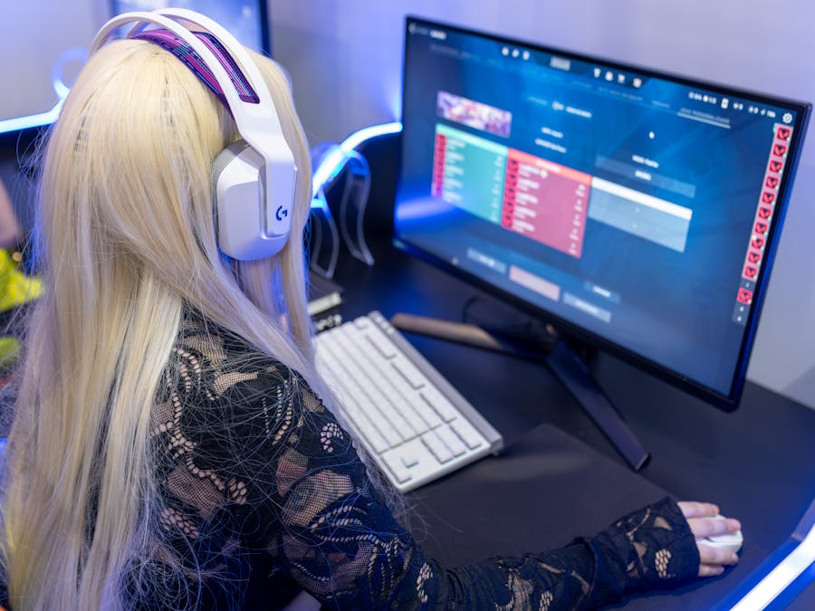 Young woman gaming at a PC high-tech setup, wearing headphones.