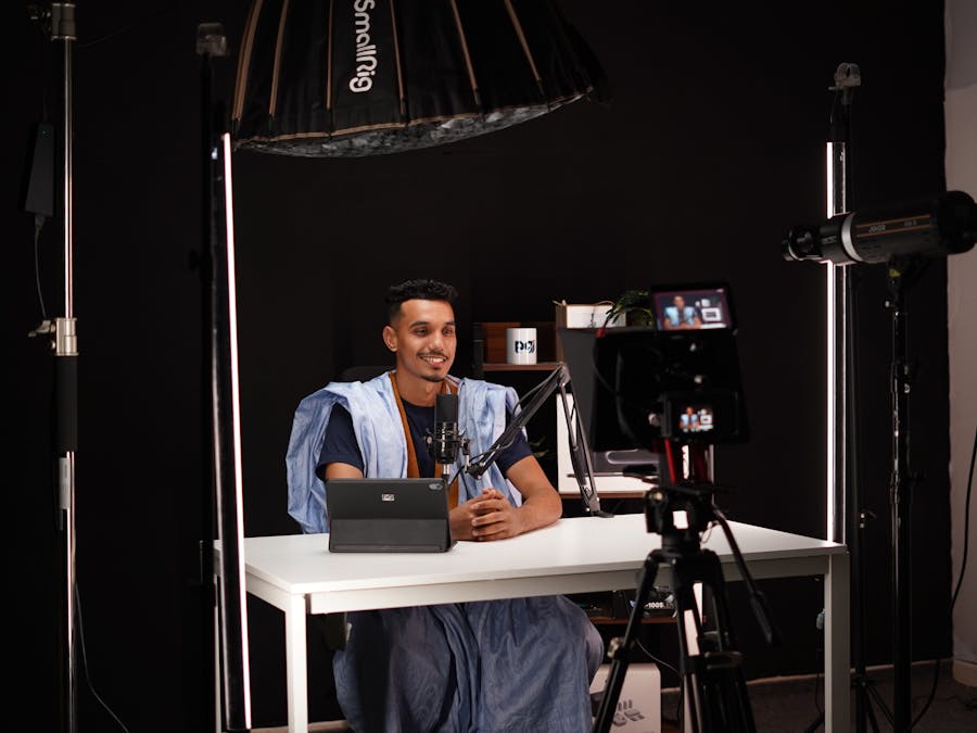 Young man recording a video in a professional studio with lighting and camera equipment.