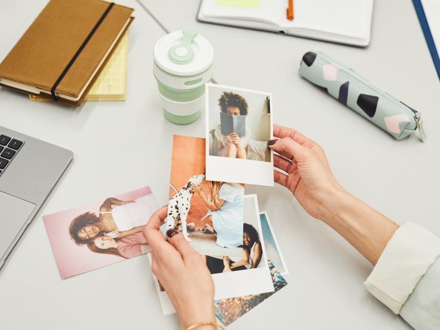 Close-up of hands holding polaroid photos on a creative workspace desk.