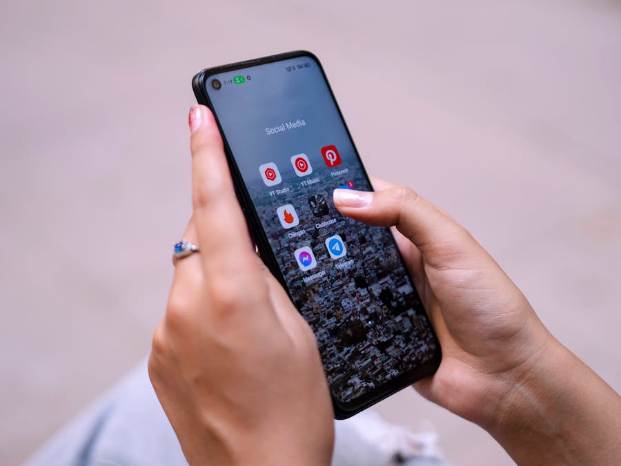 Close-up of hands holding a smartphone displaying social media apps, emphasizing digital connectivity.