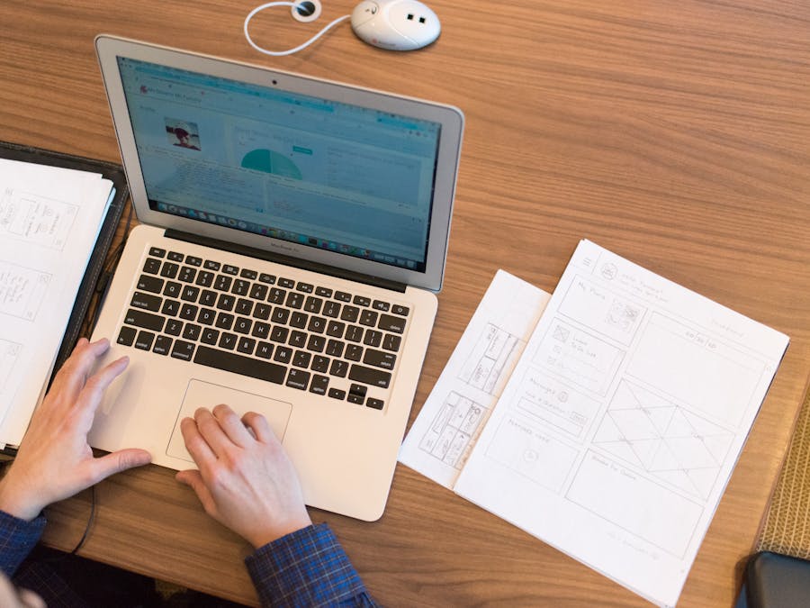 An overhead view of a person working on a laptop at a desk with documents and papers.