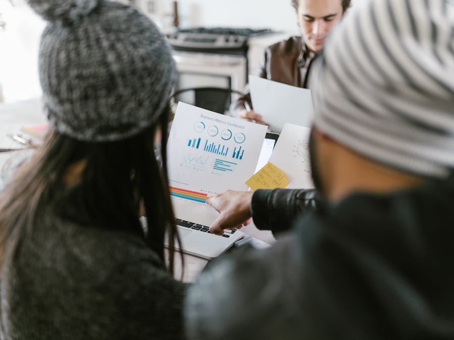 Team members discussing business metrics using printed charts in a cozy meeting space.