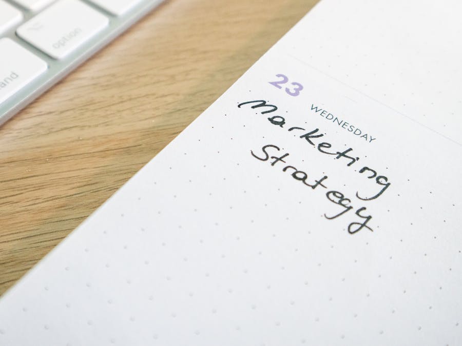 Close-up of a planner with 'Marketing Strategy' handwritten alongside keyboard.