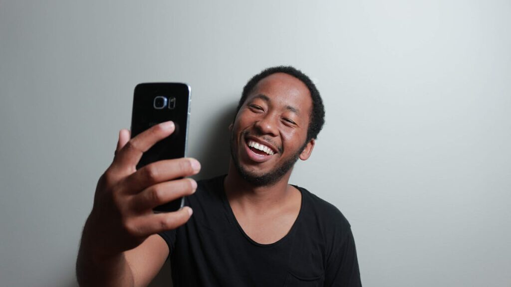 Happy man capturing a cheerful selfie with smartphone indoors.
