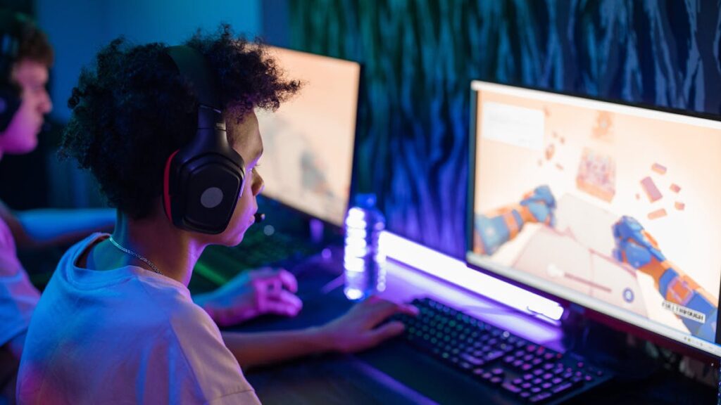 Teen gamers engrossed in online computer game in a vibrant, modern gaming room.