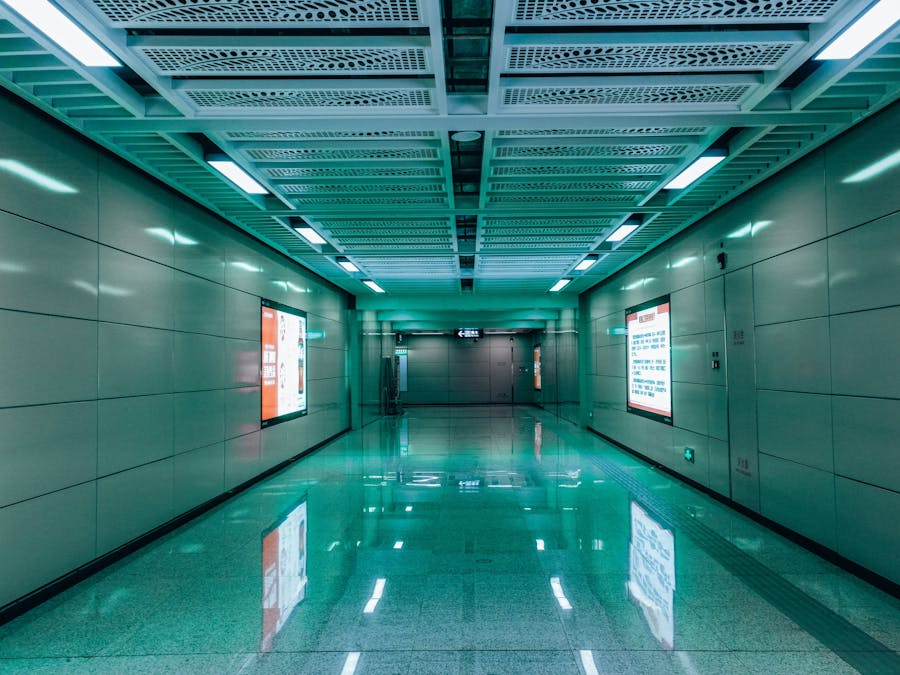 Futuristic metro tunnel with illuminated advertising screens and reflective flooring, highlighting a modern transit space.