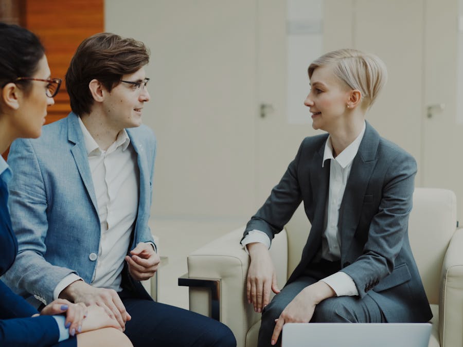 Three professionals engaging in a conversation during a business meeting indoors.