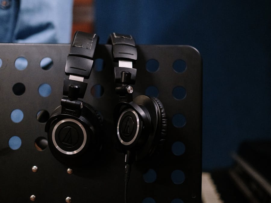 Close-up of professional headphones hanging on a perforated music stand in a studio setting.